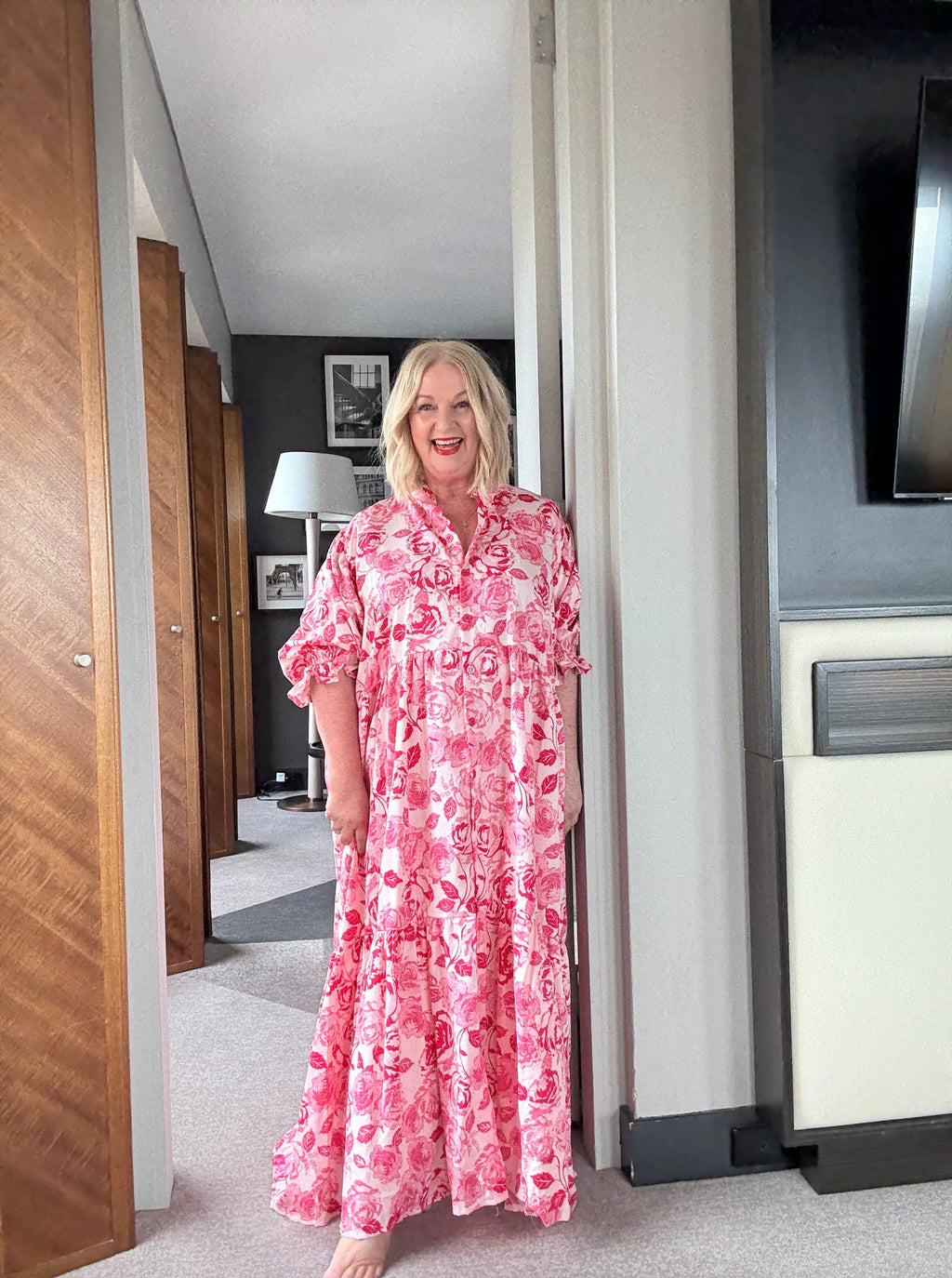 Woman in a pink floral dress standing on a moving platform elevator.