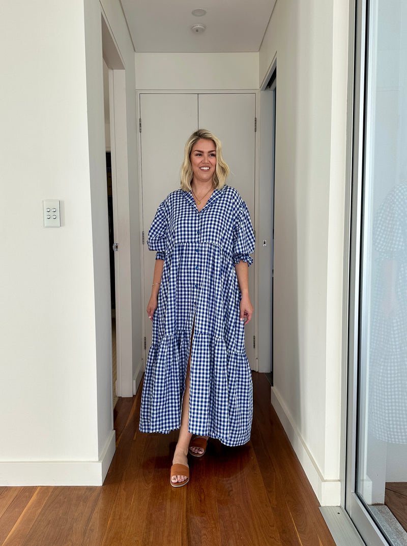 Woman wearing a blue checkered dress in a home interior setting