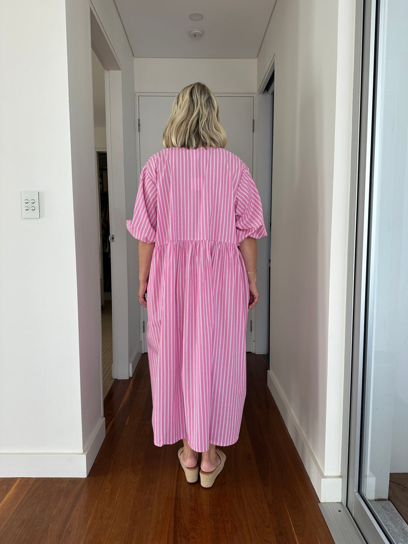 Person wearing a pink dress standing inside a kitchen.