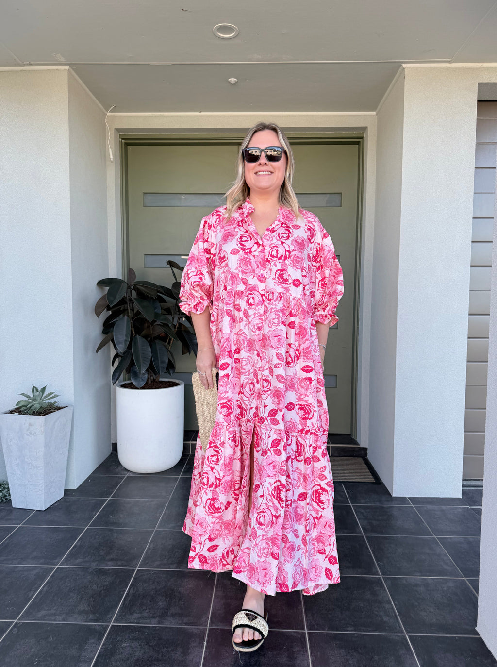 Person wearing a pink floral dress standing in a room with a door and tiled floor.